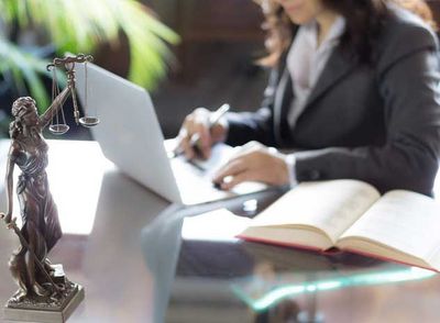 Statue of Justice with scales and lawyer working on a laptop