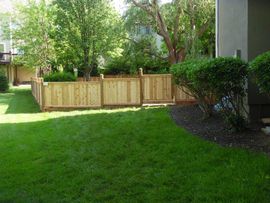 a wooden fence surrounds a lush green yard