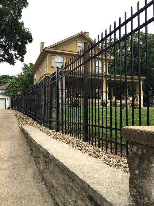 a black metal fence surrounds a large house .