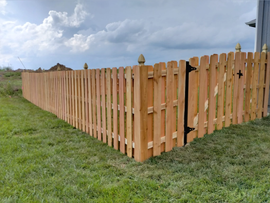 a wooden fence is sitting in the middle of a lush green field .