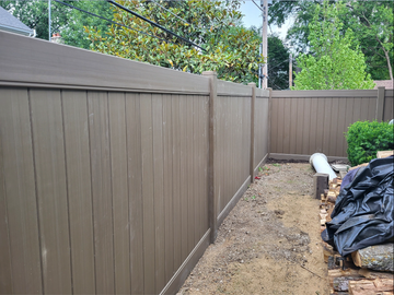 a brown wooden fence surrounds a dirt area in a backyard .