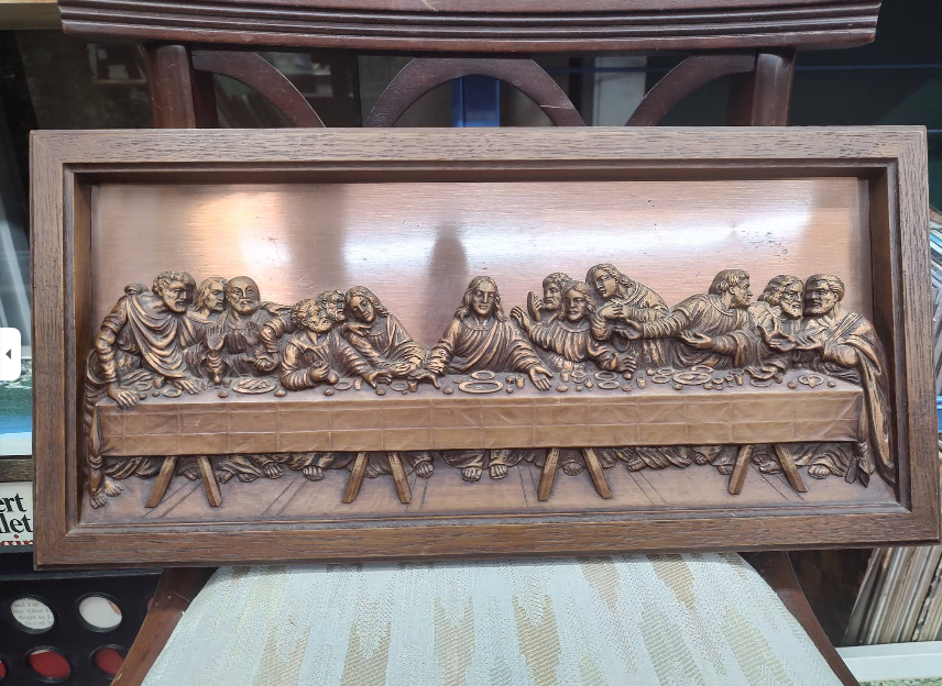 Wooden carving of the Last Supper, depicting Jesus and his disciples seated at a table in a detailed relief.