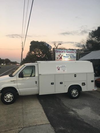 White work van parked near a sign for Gracie's Goodies. Evening sky in the background.
