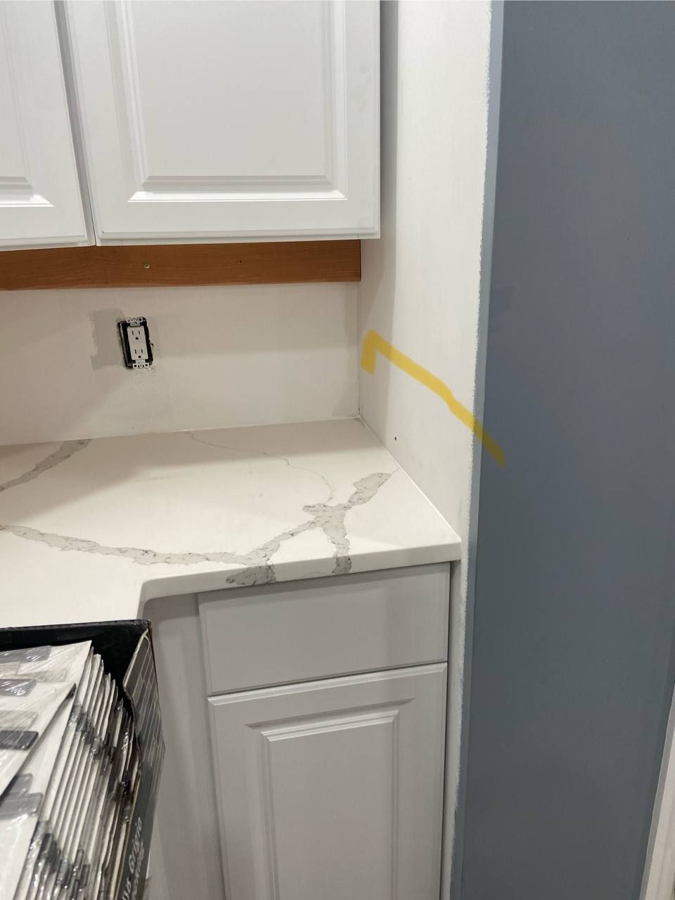 A kitchen with white cabinets and a white counter top.