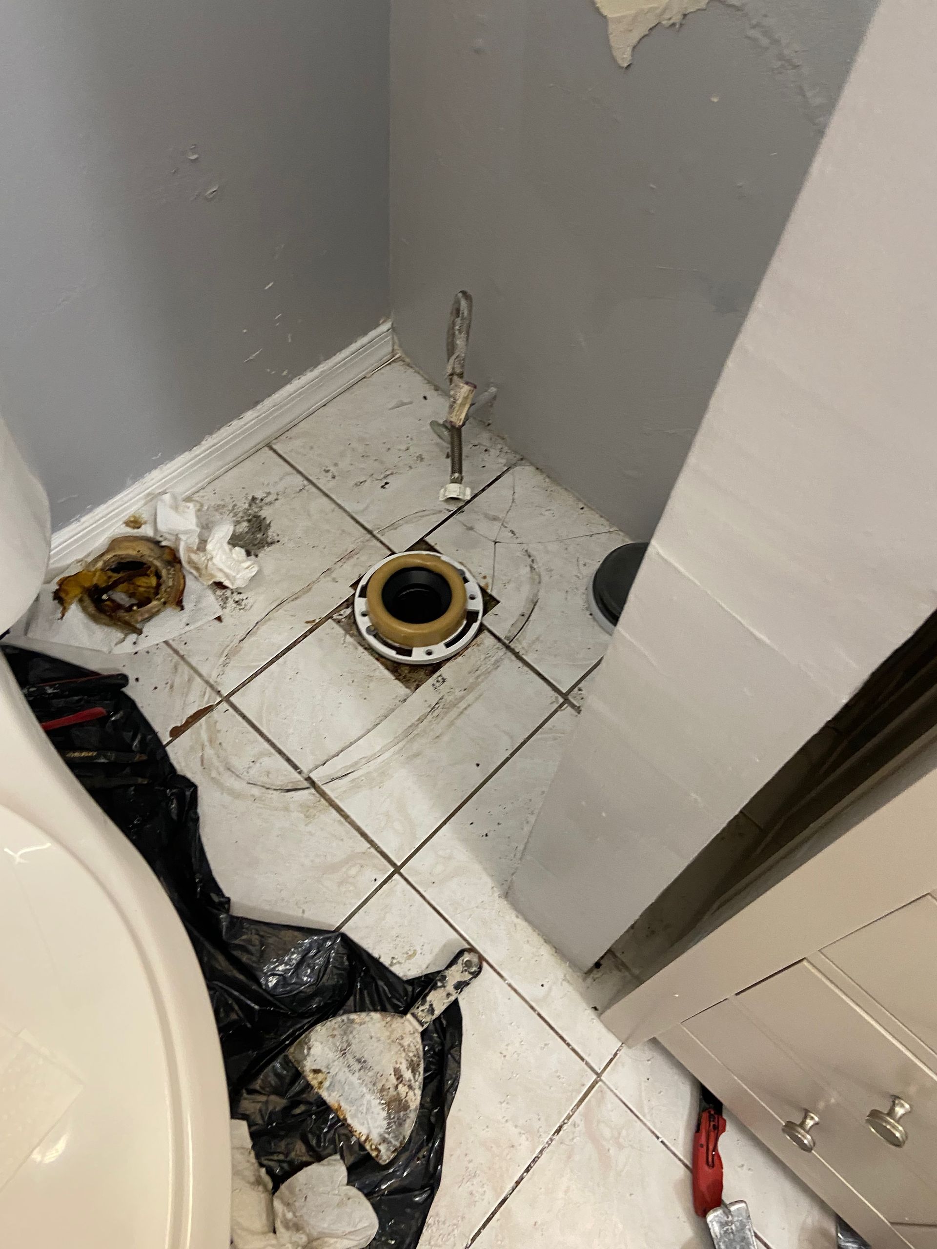 A toilet is sitting on a tiled floor in a bathroom.