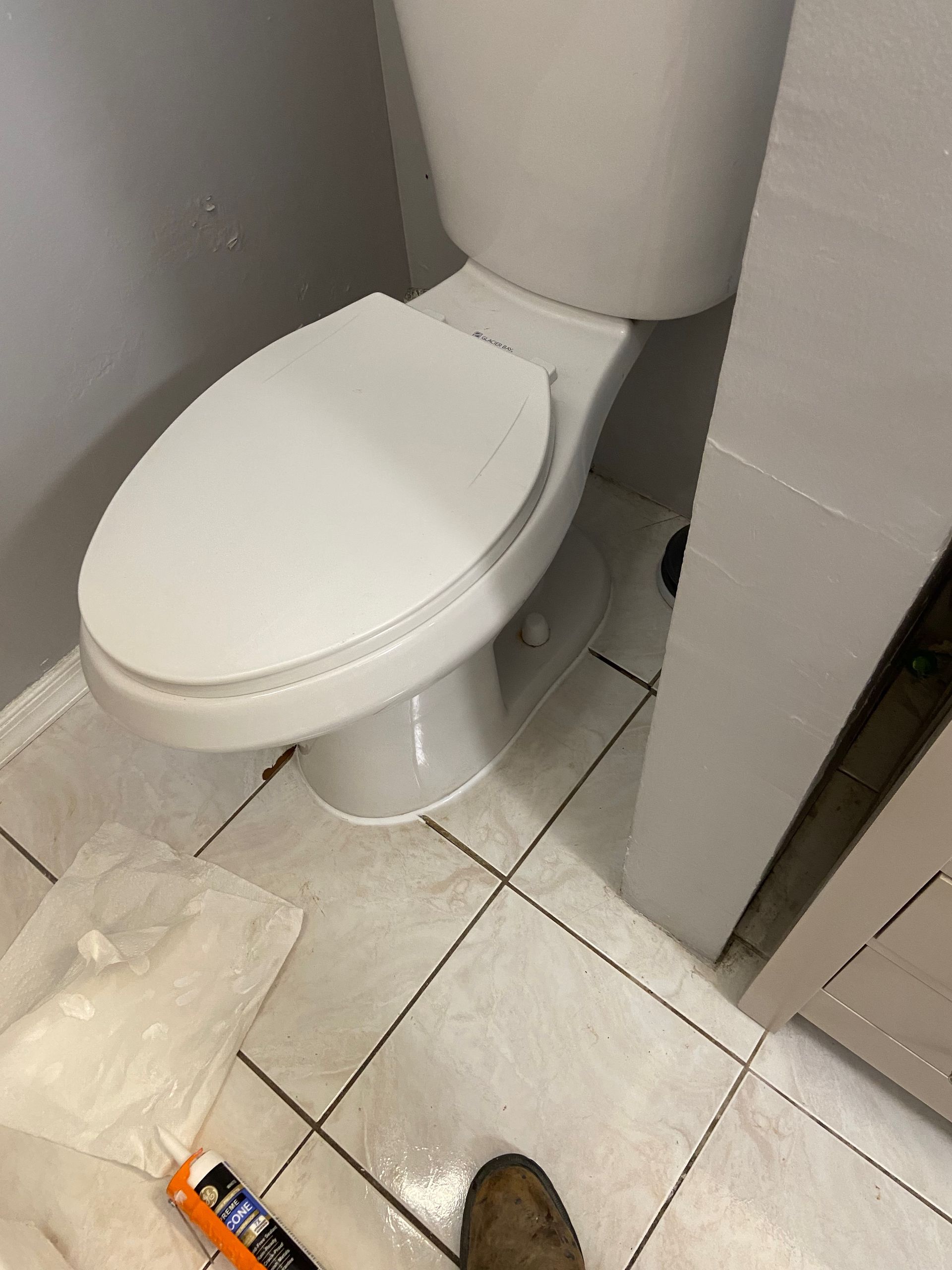 A toilet is sitting on a tiled floor in a bathroom.