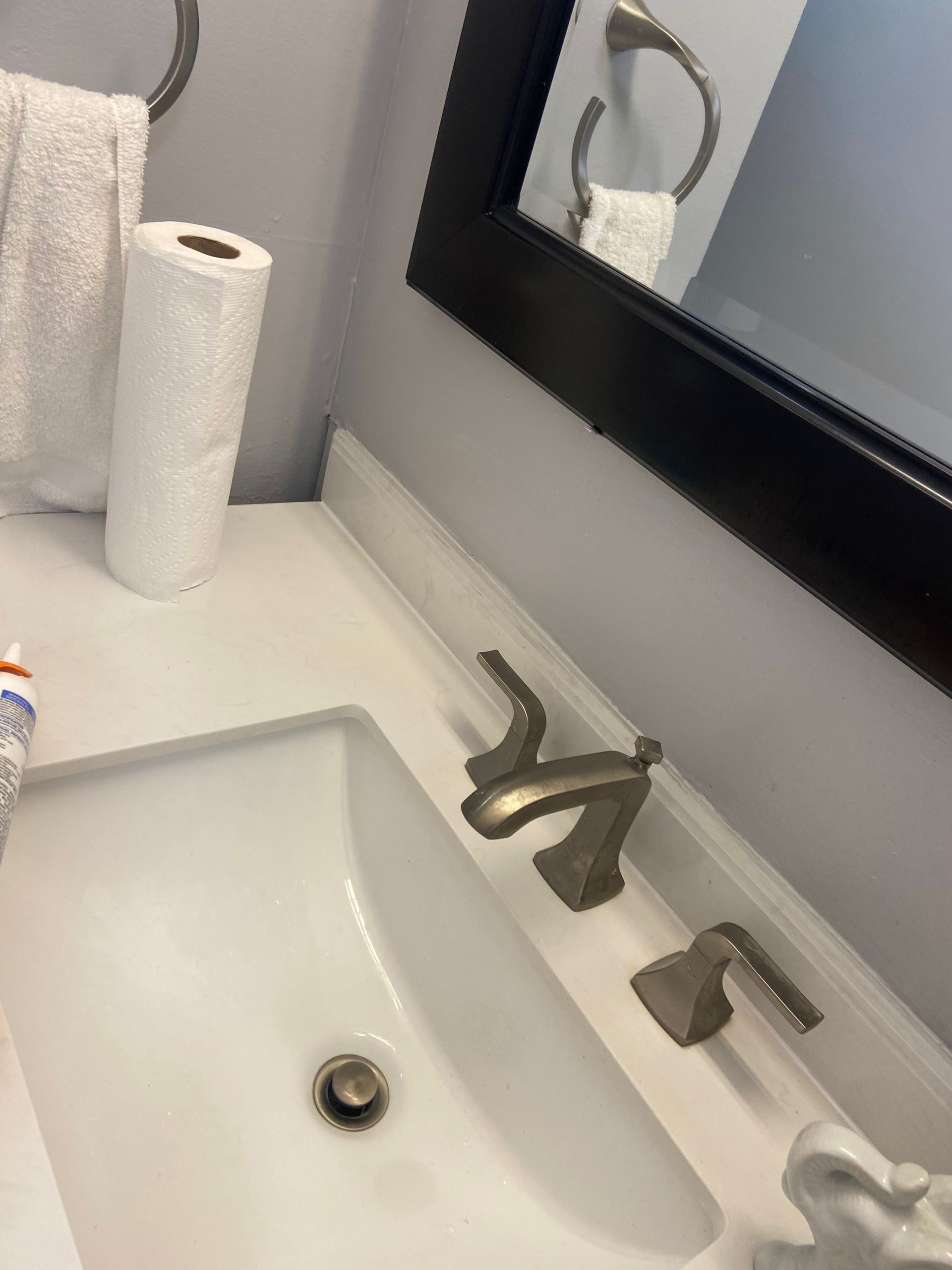 A bathroom sink with a mirror and a roll of toilet paper