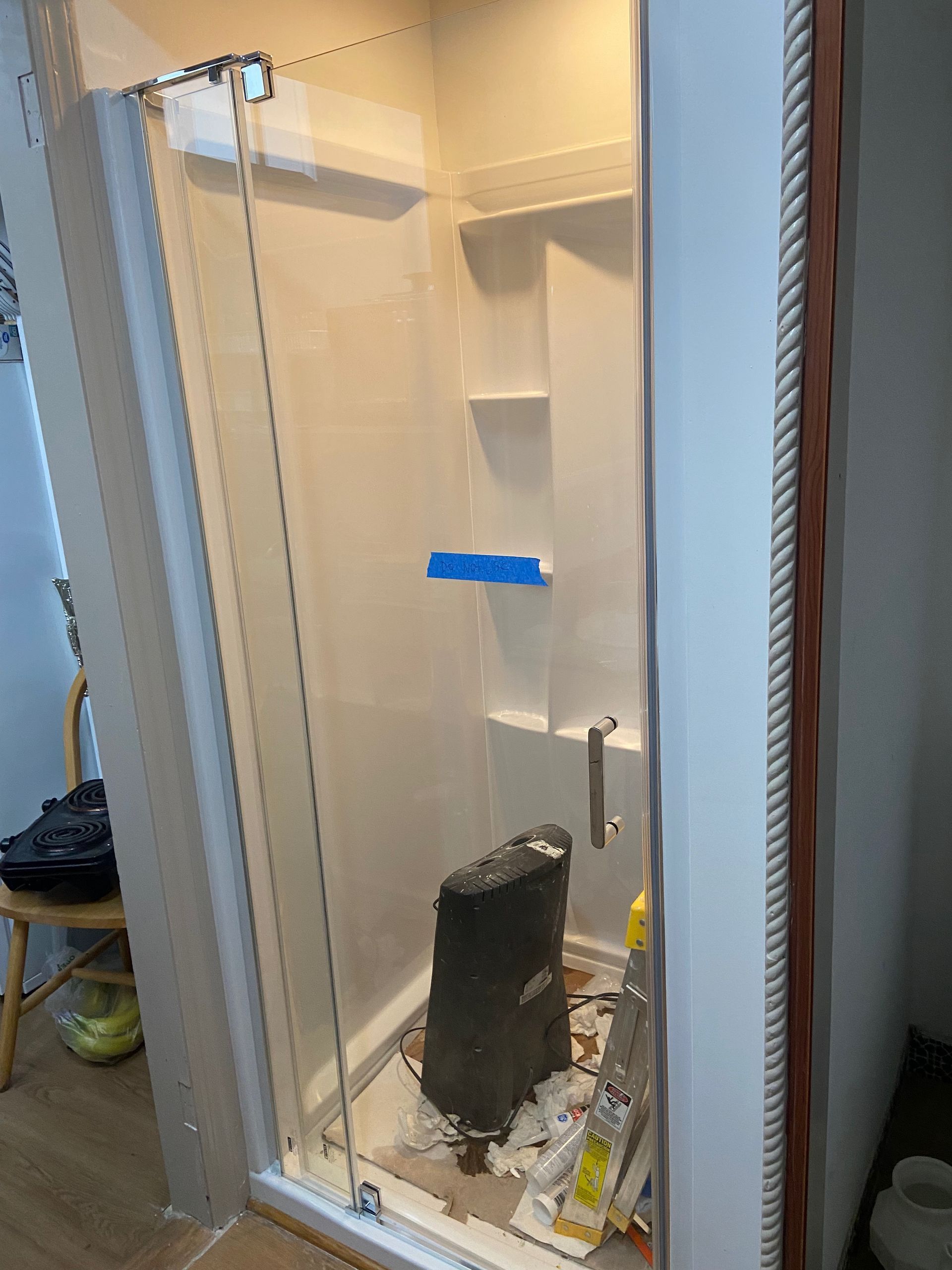 A shower stall with a sliding glass door is being built