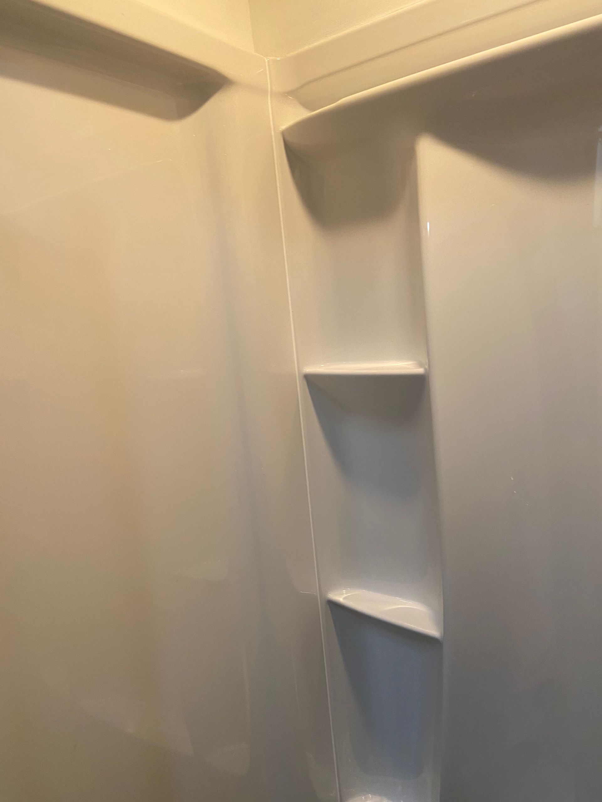 A bathroom with a shower stall and shelves on the wall.