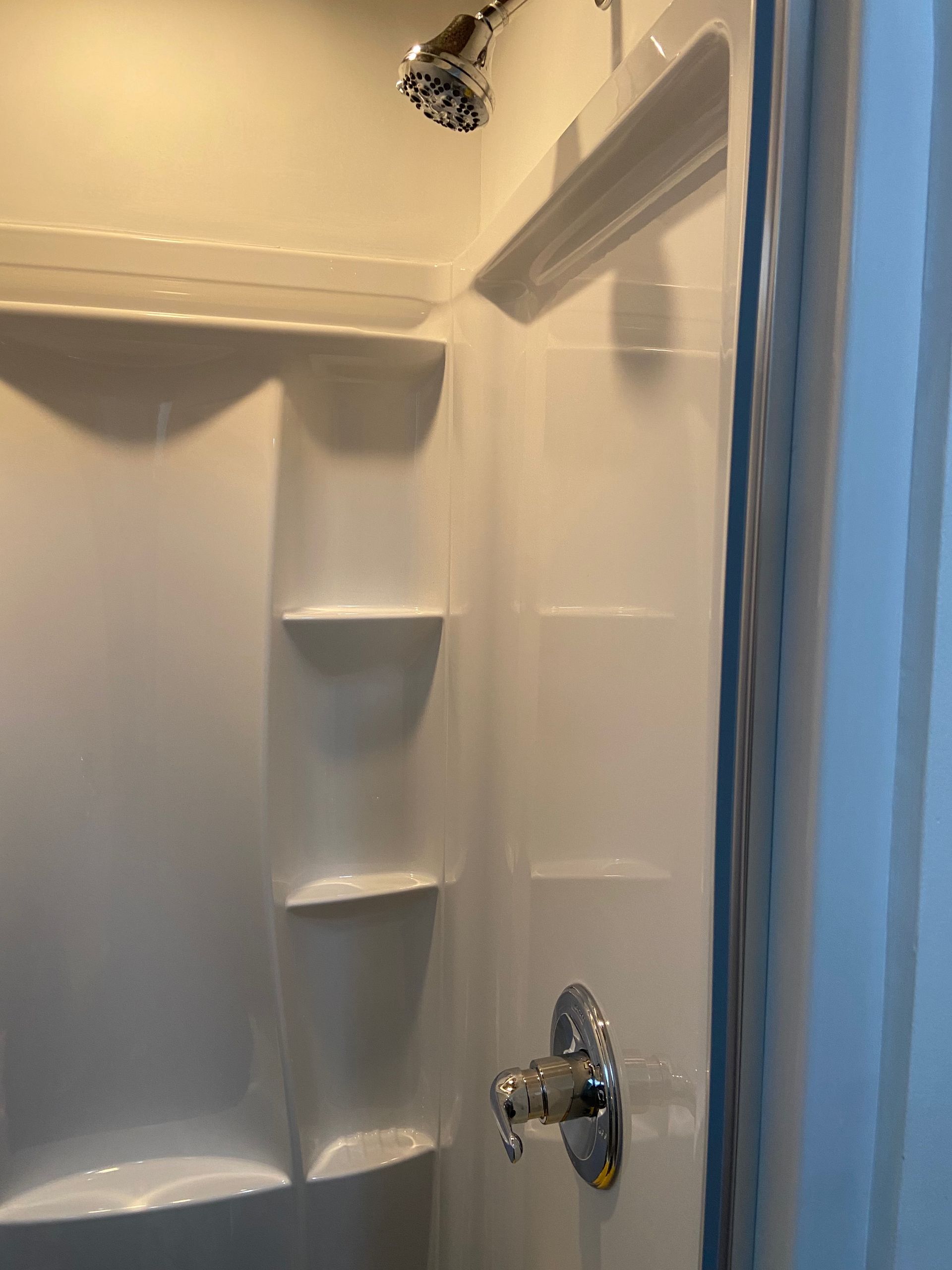 A shower stall with shelves and a shower head