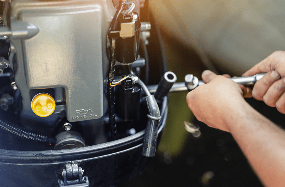 Hands using a wrench to work on a black boat engine.