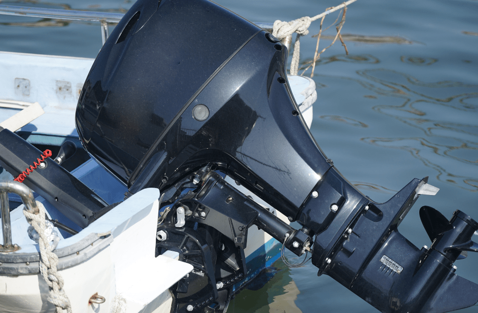 Black outboard motor attached to a white and blue boat, in a body of water.