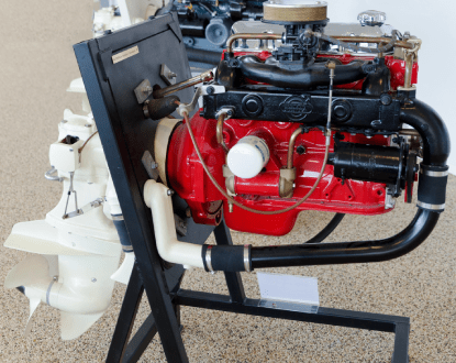 Red boat engine with white outdrive on a black stand.