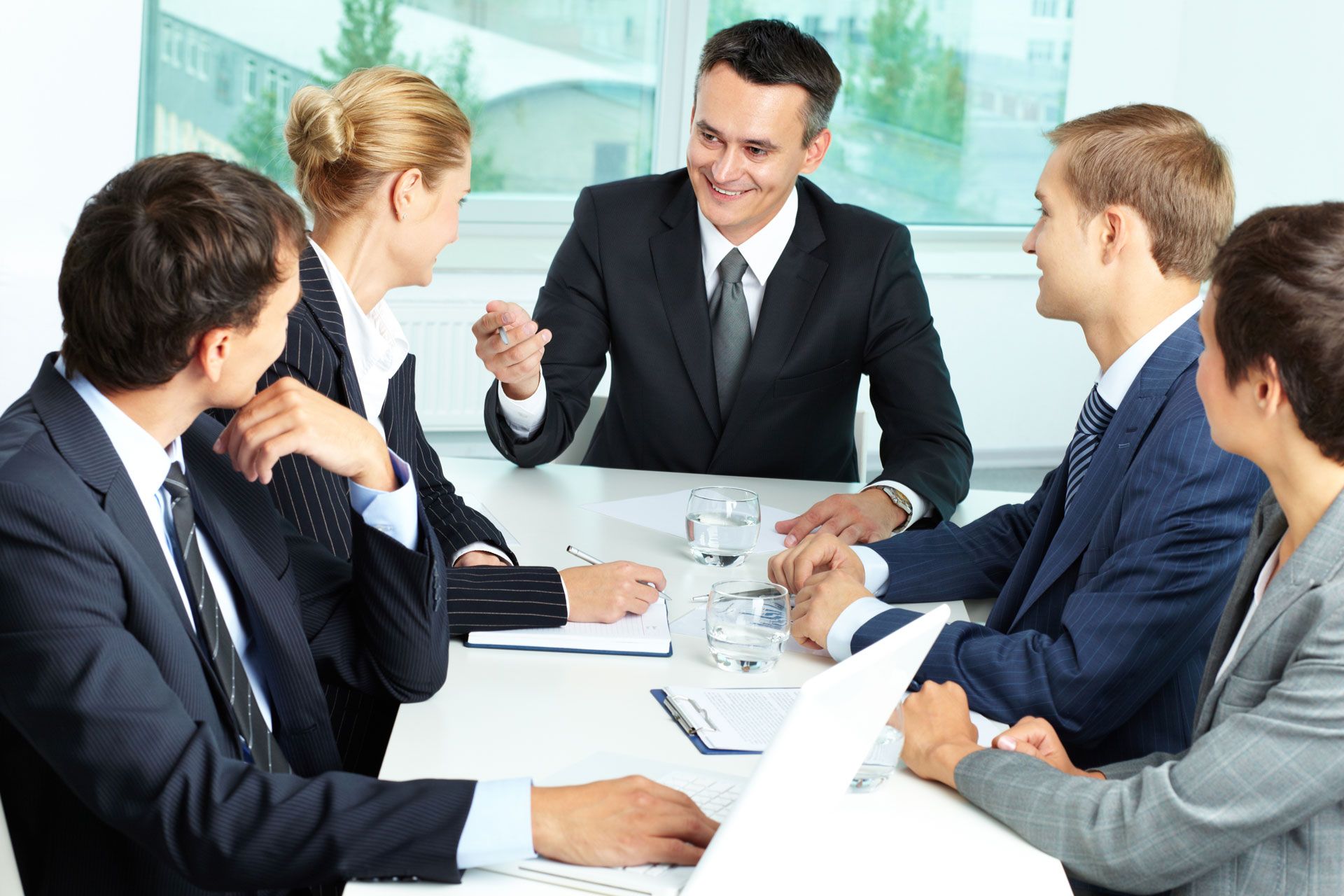 Business team in suits at a meeting, discussing ideas around a table.