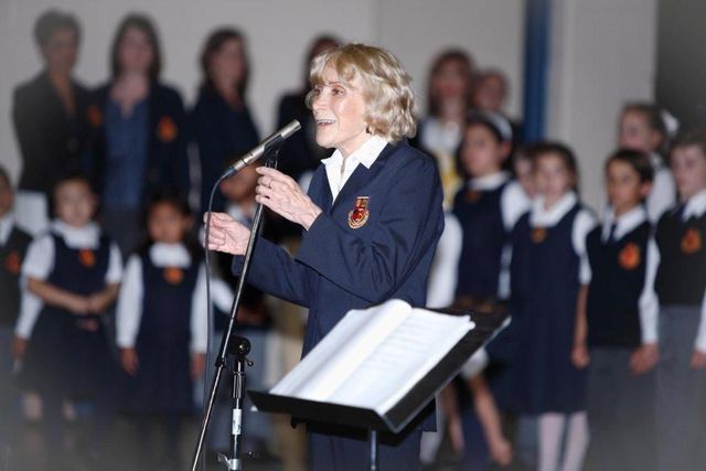 A woman singing into a microphone in front of a choir