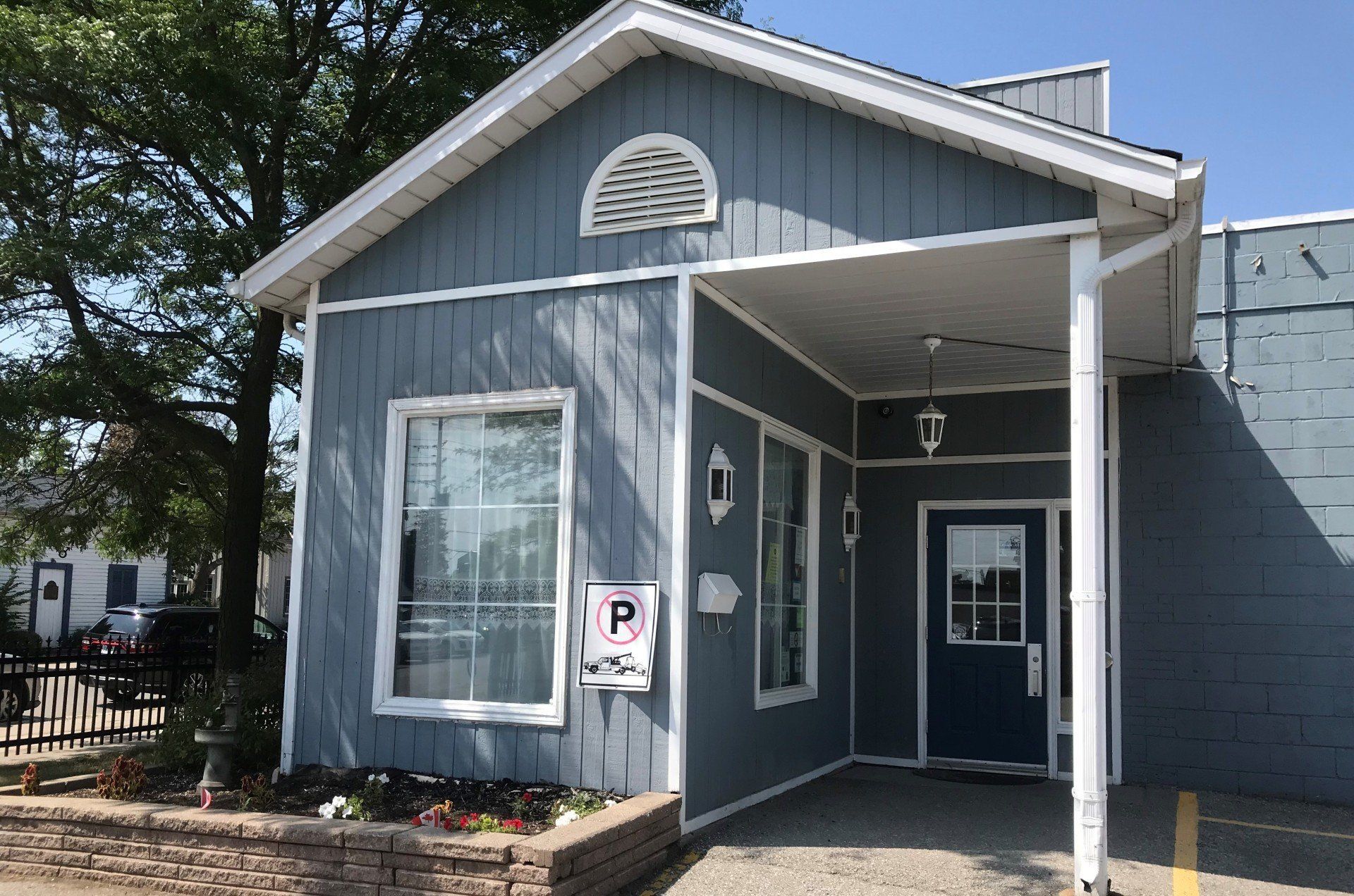 A small blue house with a porch and a blue door.