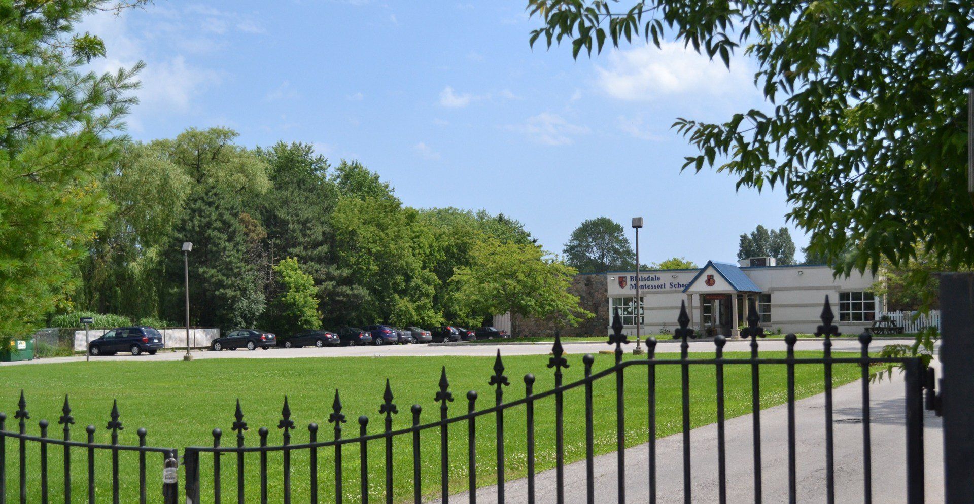 A fence surrounds a grassy field with a building in the background