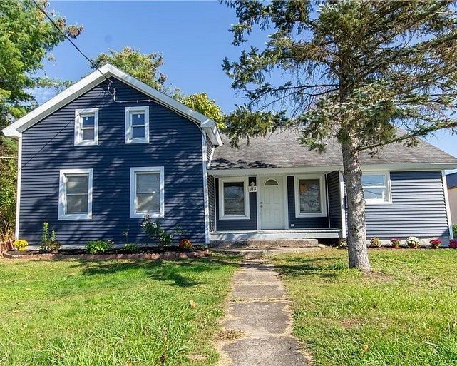 A blue house with white trim and a tree in front of it.