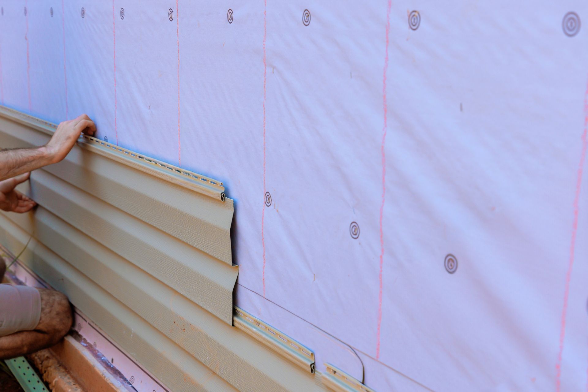 A person is installing siding on a wall.