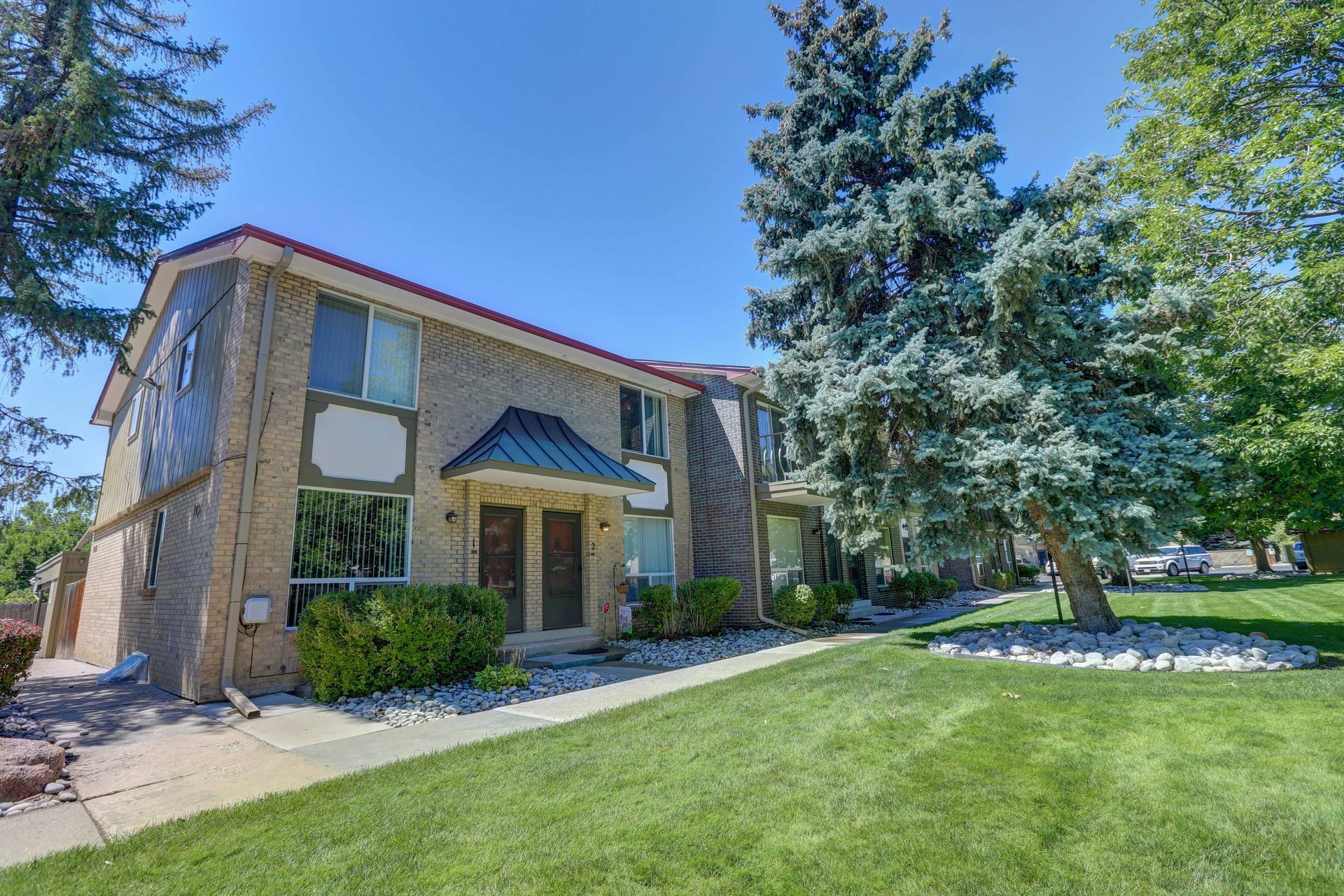 A brick apartment building with a lush green lawn in front of it.