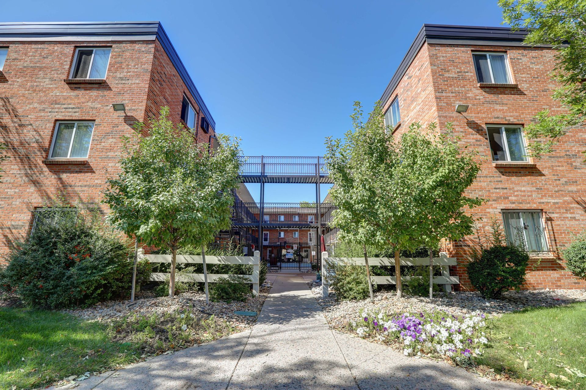 A brick apartment building with a walkway leading to it.