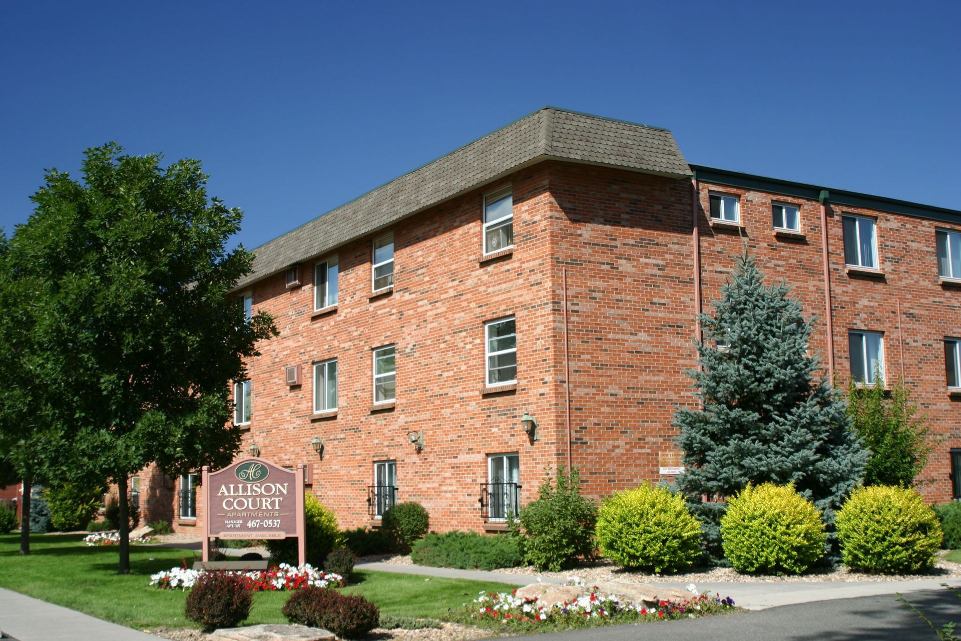 A large brick apartment building with a sign in front of it