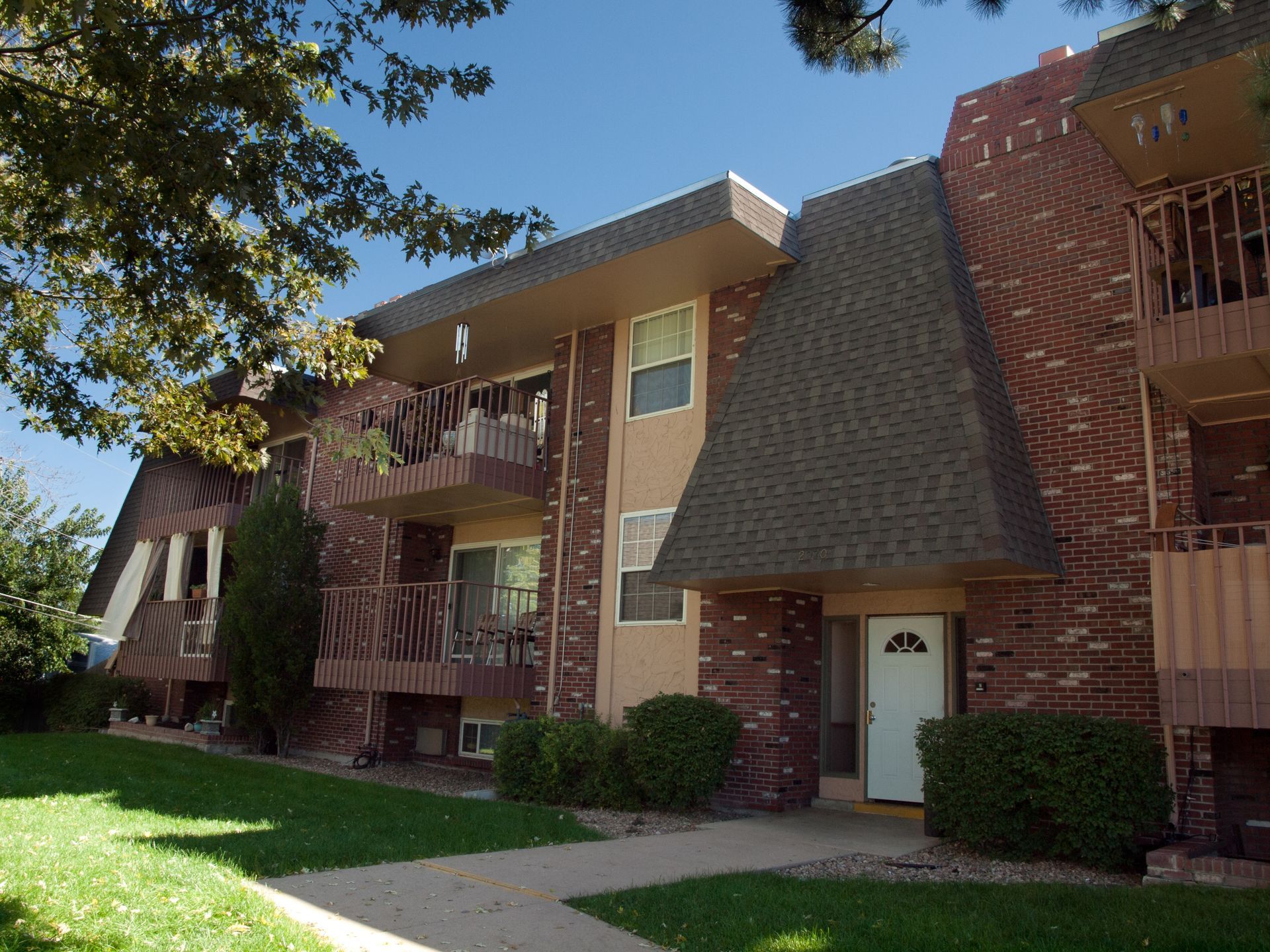 A brick apartment building with balconies and a white door