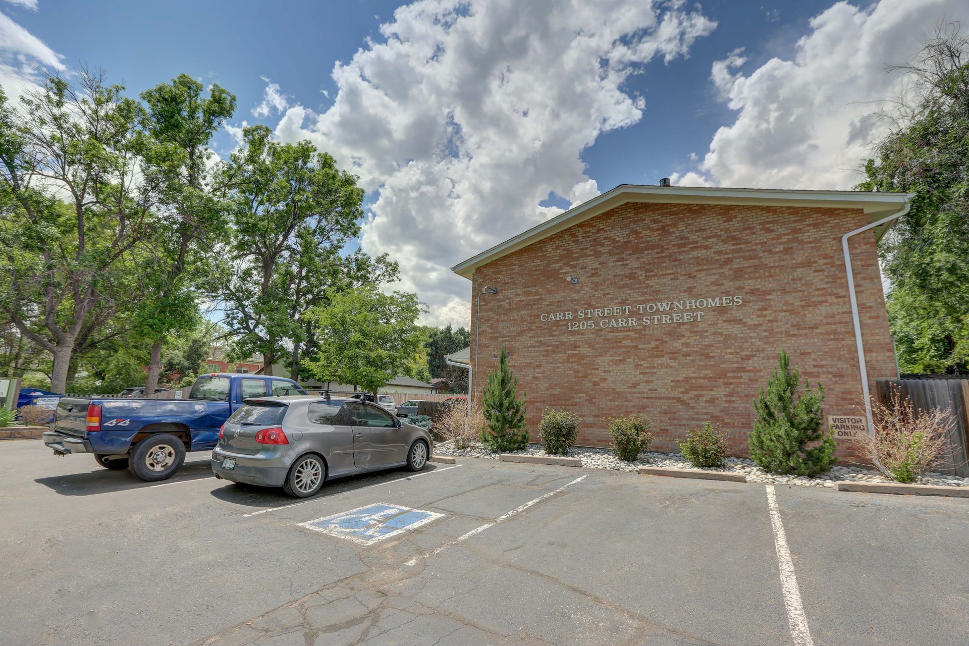 A parking lot with cars parked in front of a brick building.