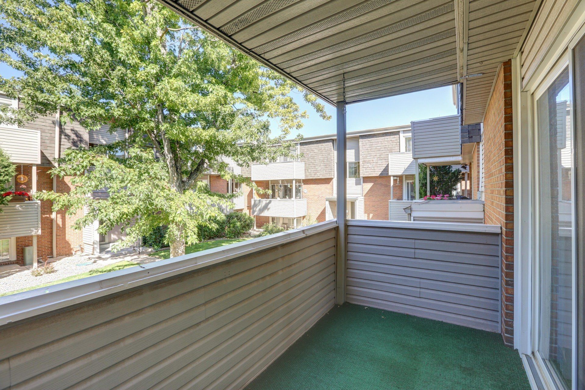 A balcony with a sliding glass door and a view of a brick building.