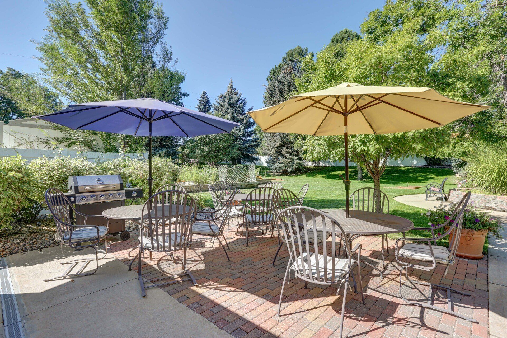 A patio with tables and chairs and umbrellas on a sunny day.
