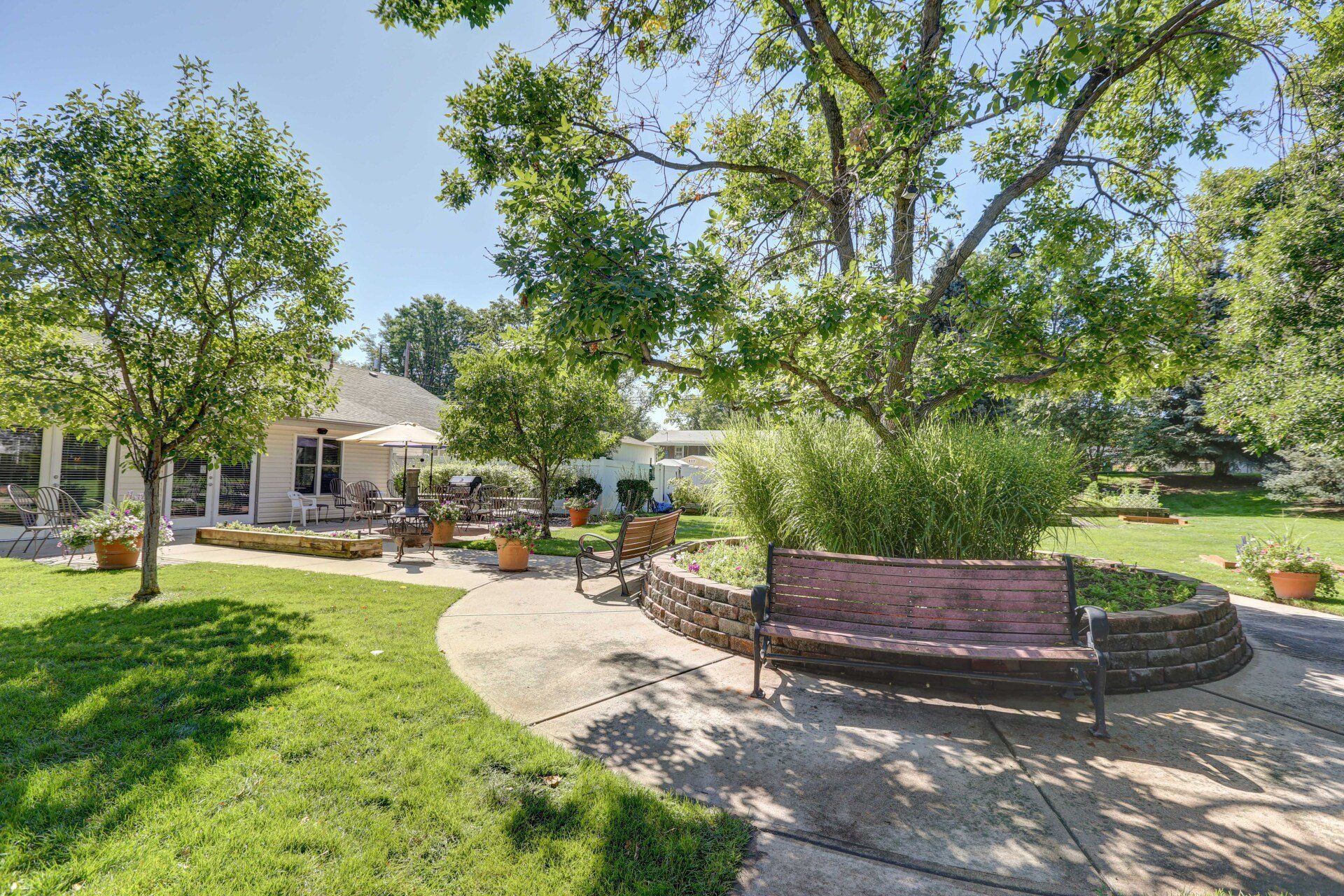 A park with a bench and trees in front of a house.