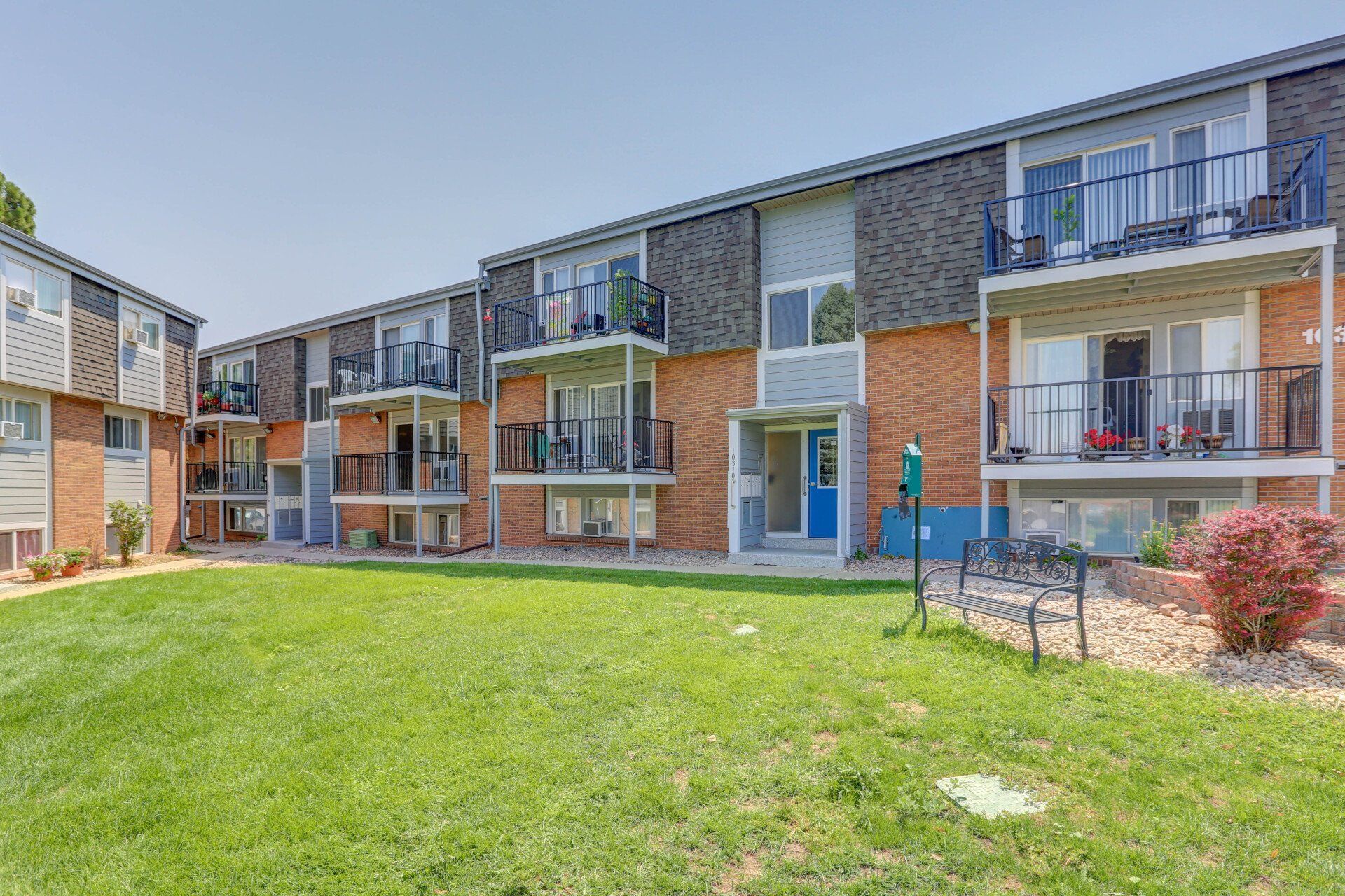 A large apartment building with a lush green lawn in front of it.