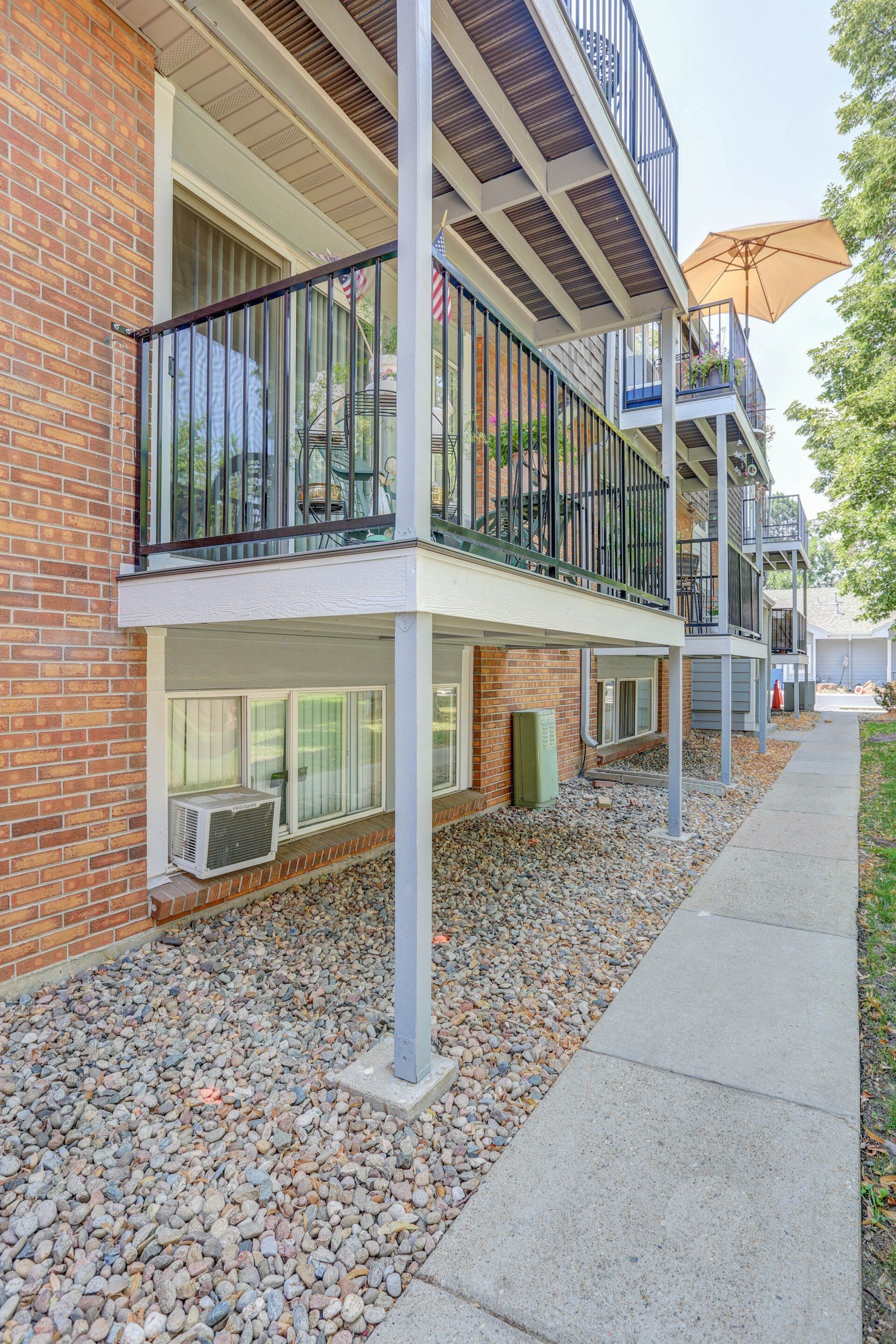 A sidewalk leading to a brick apartment building with balconies.