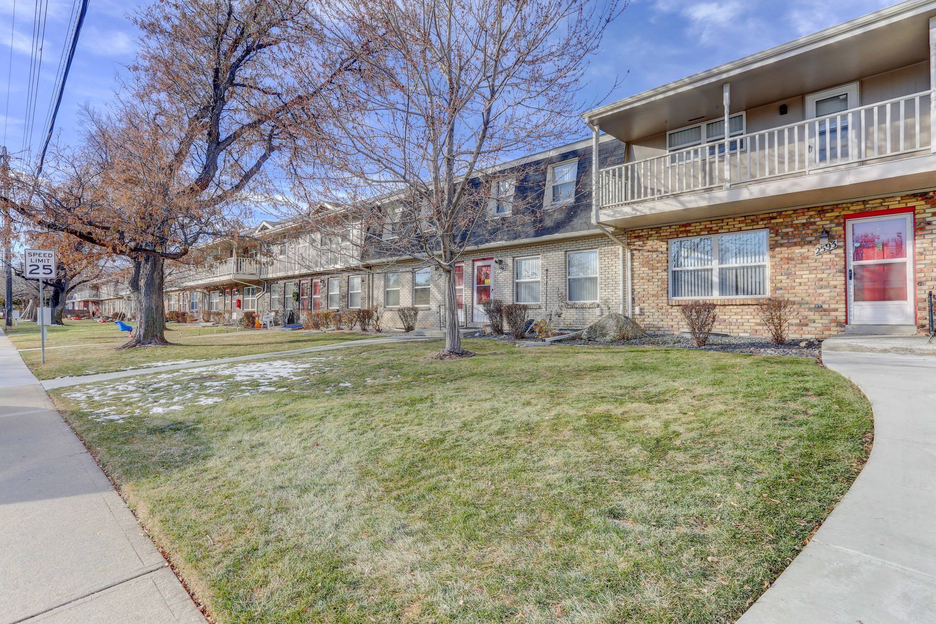 A brick apartment building with a lush green lawn in front of it.