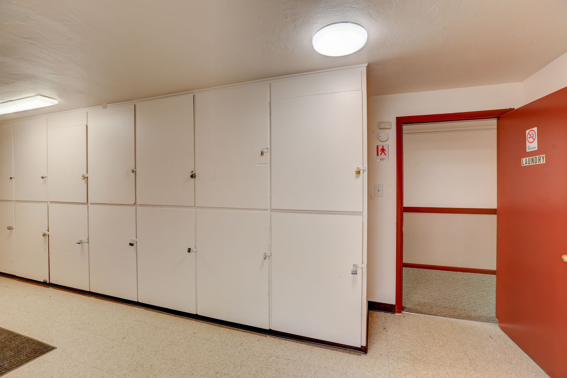 A hallway with white cabinets and a red door