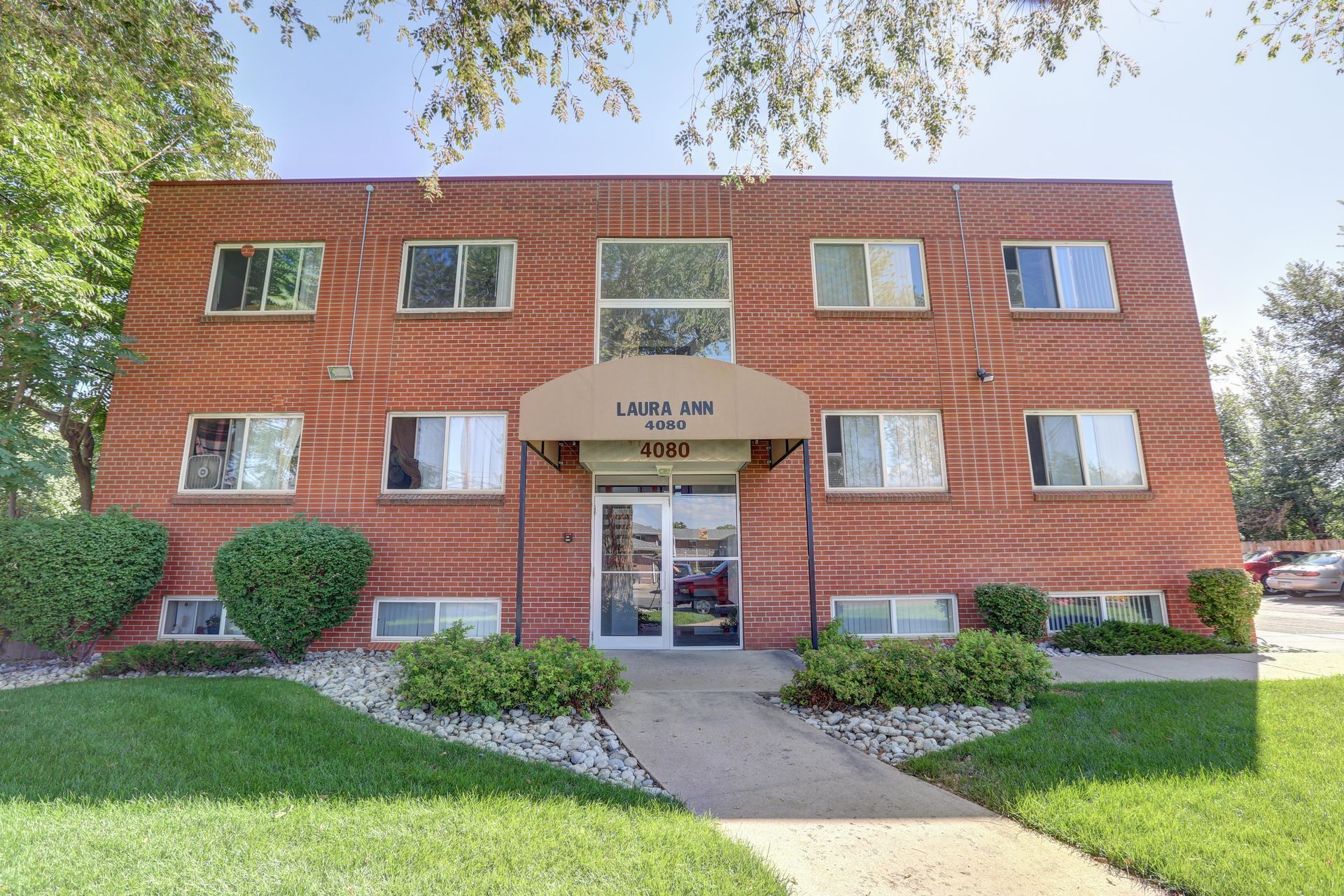 A brick apartment building with a tan awning over the entrance