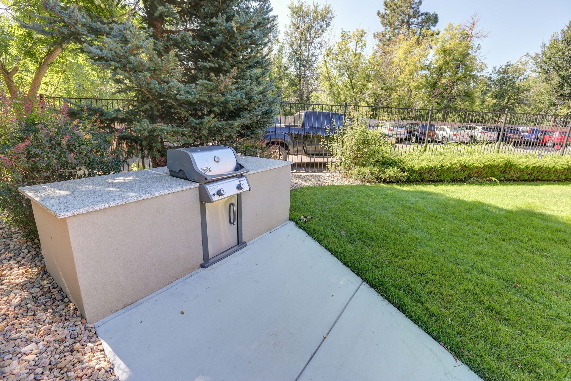 A grill is sitting on a concrete patio next to a lush green lawn.