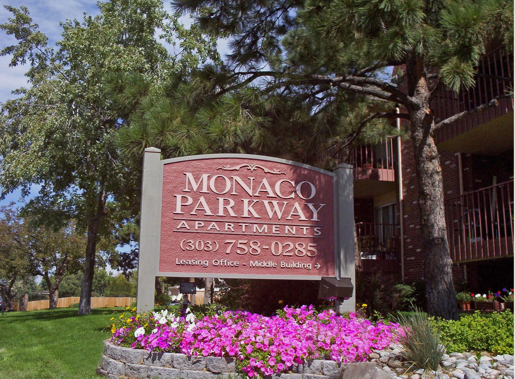 A sign for monaco parkway apartment is in front of a building