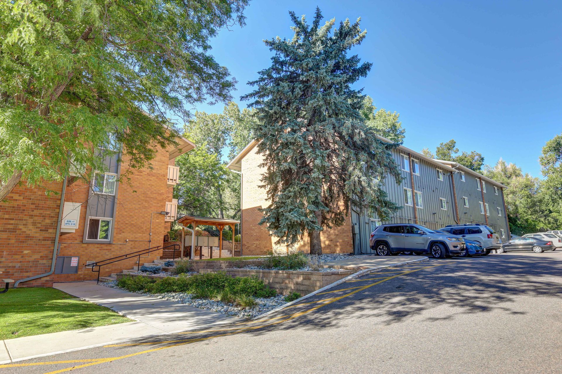 A brick apartment building with cars parked in front of it.