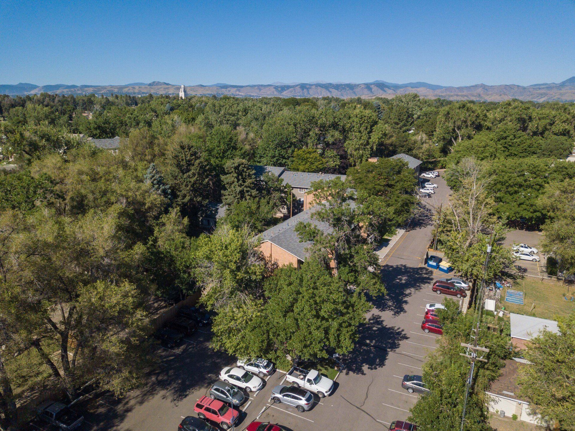 An aerial view of a parking lot surrounded by trees and houses.