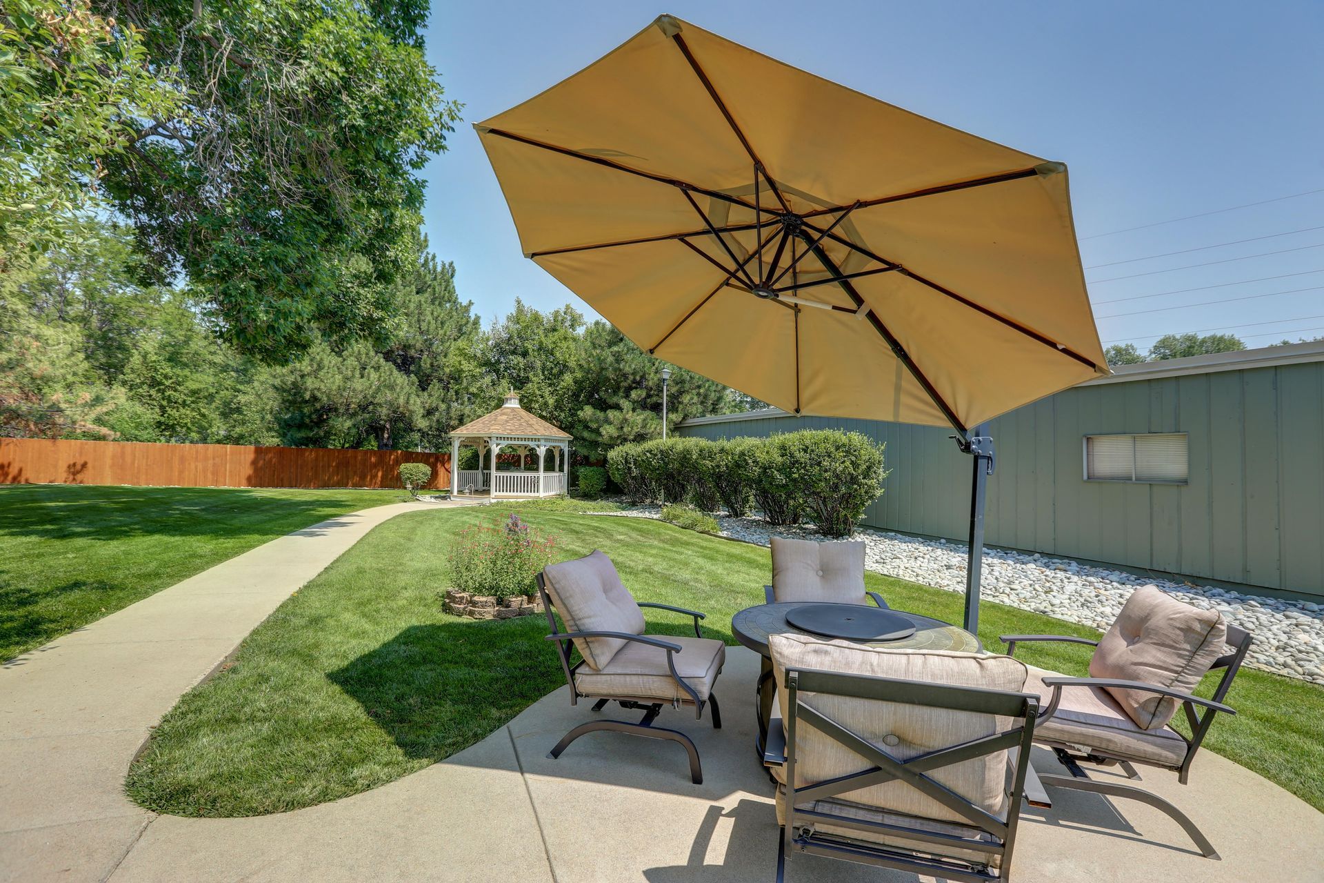 A patio with a large umbrella and a gazebo in the background