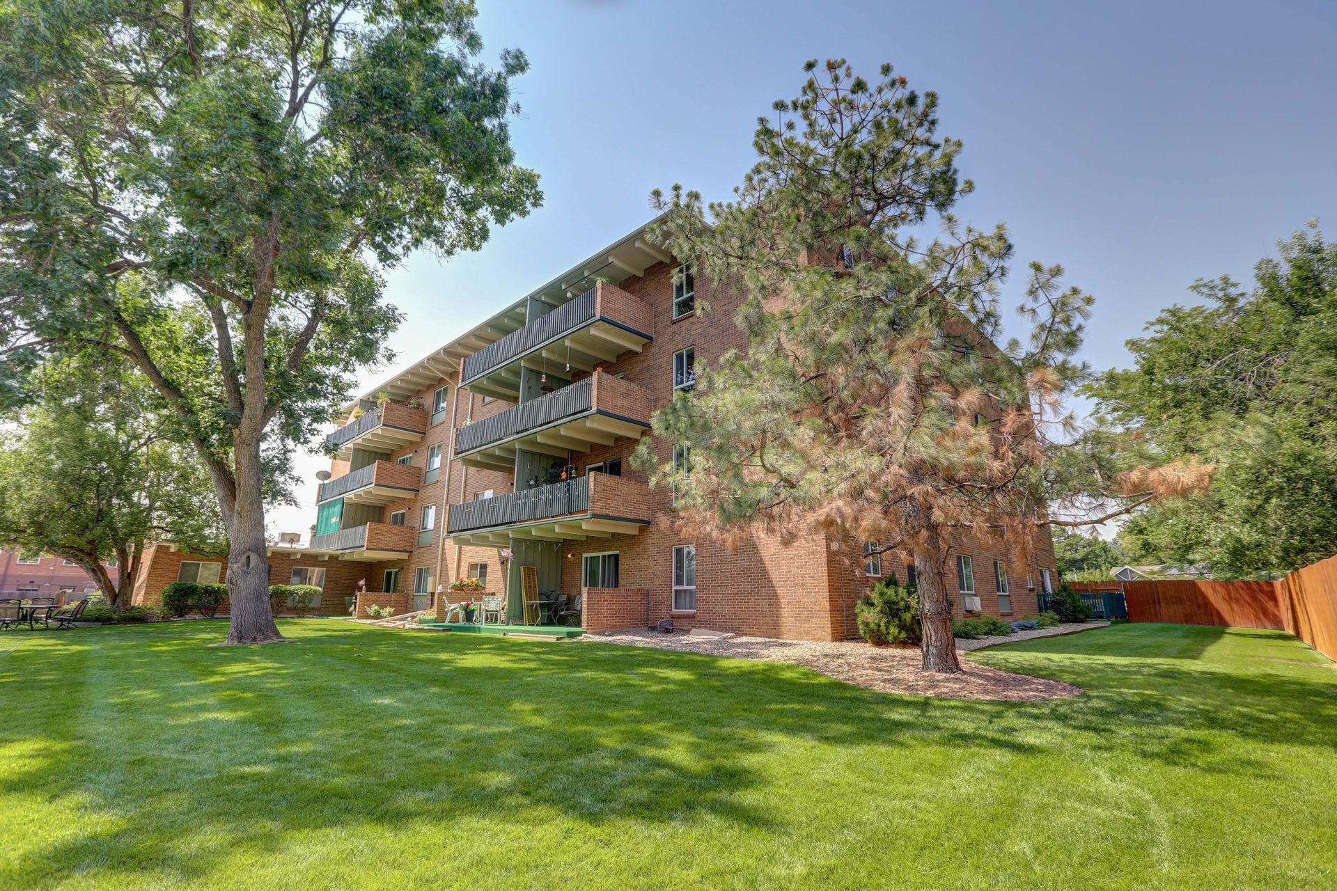A large brick apartment building with a lush green lawn in front of it.
