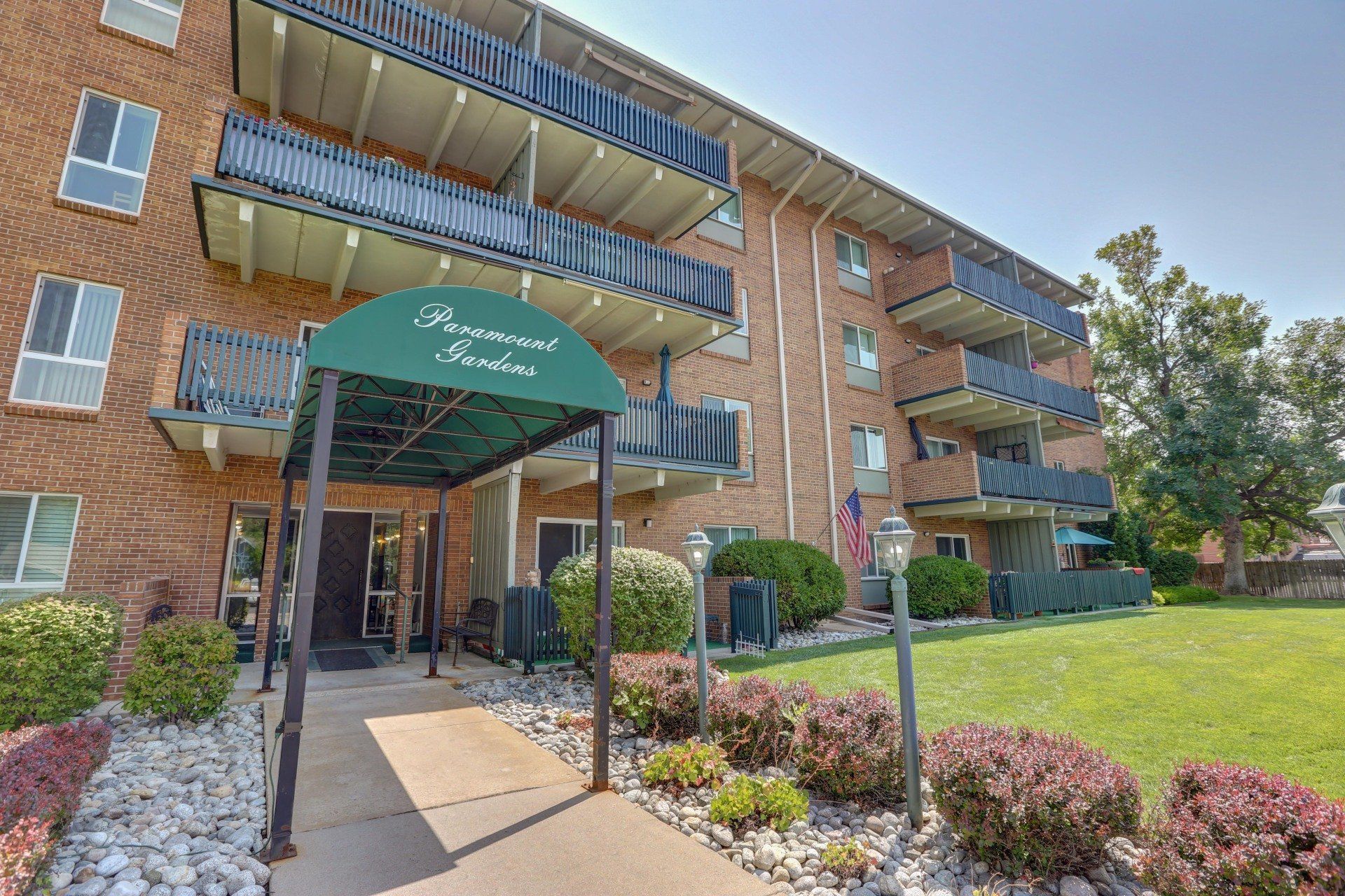 A large brick apartment building with a green awning over the entrance.