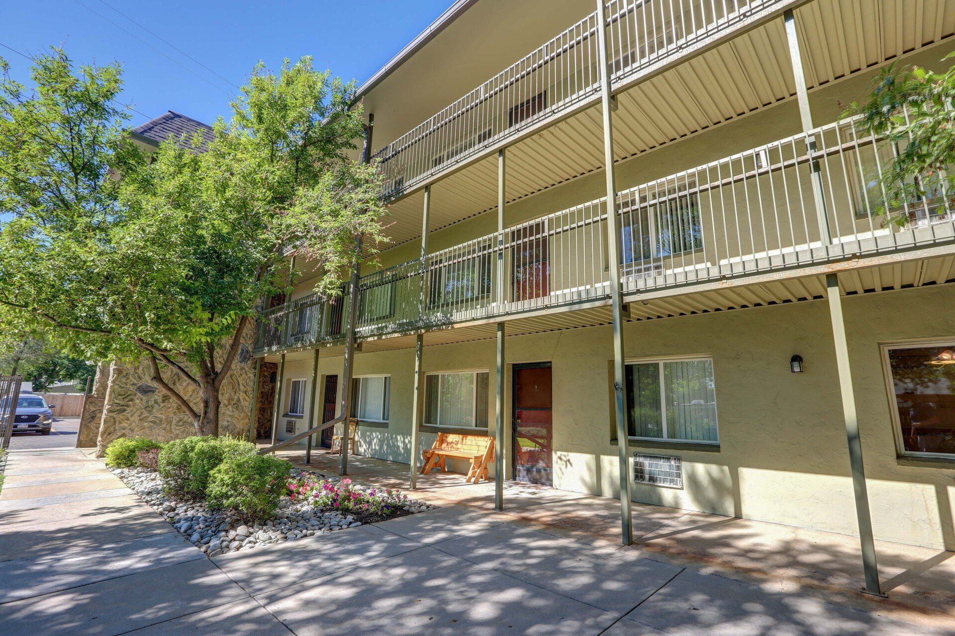 A large apartment building with balconies and trees in front of it.