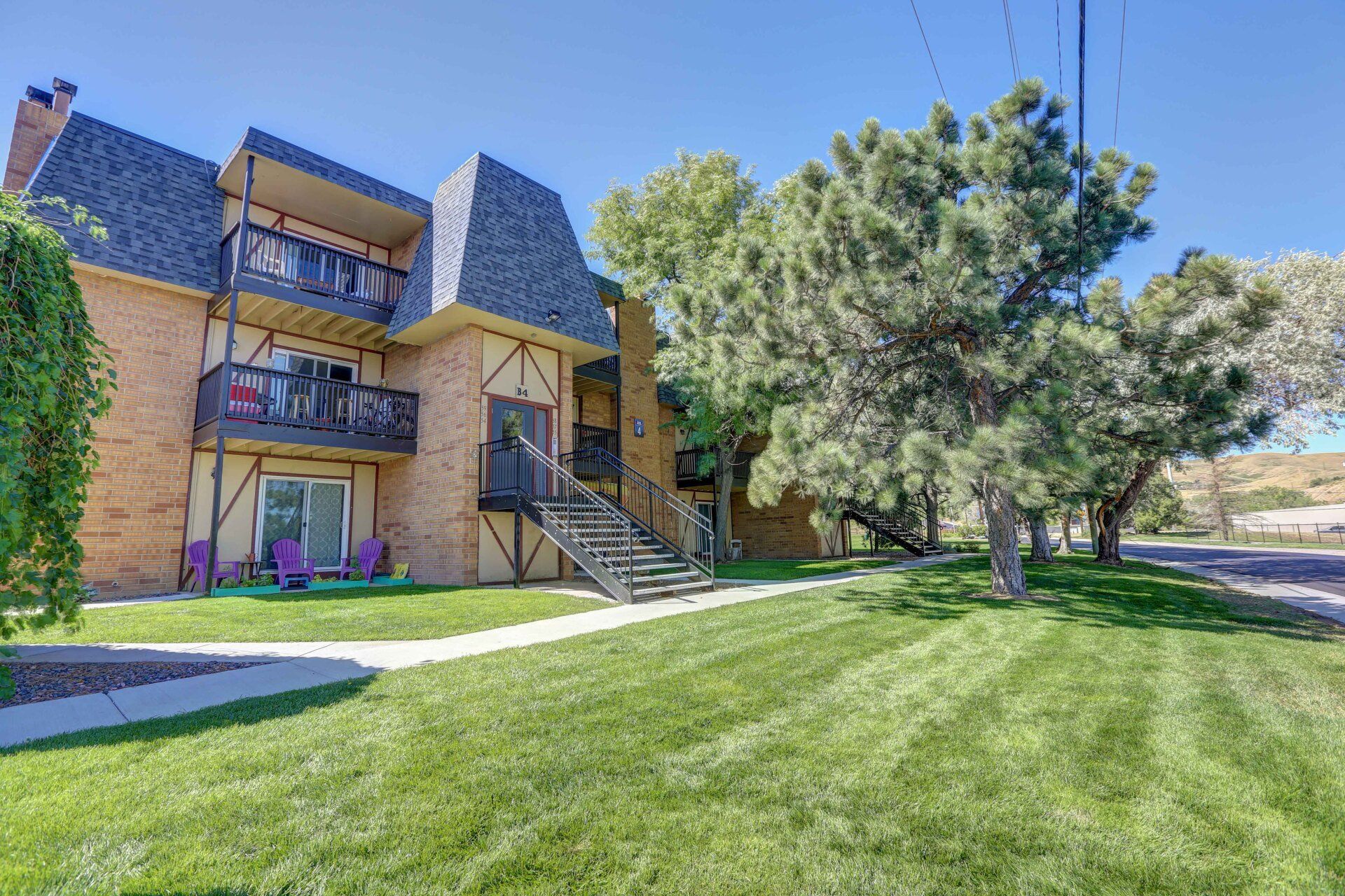 A large apartment building with a lush green lawn in front of it.