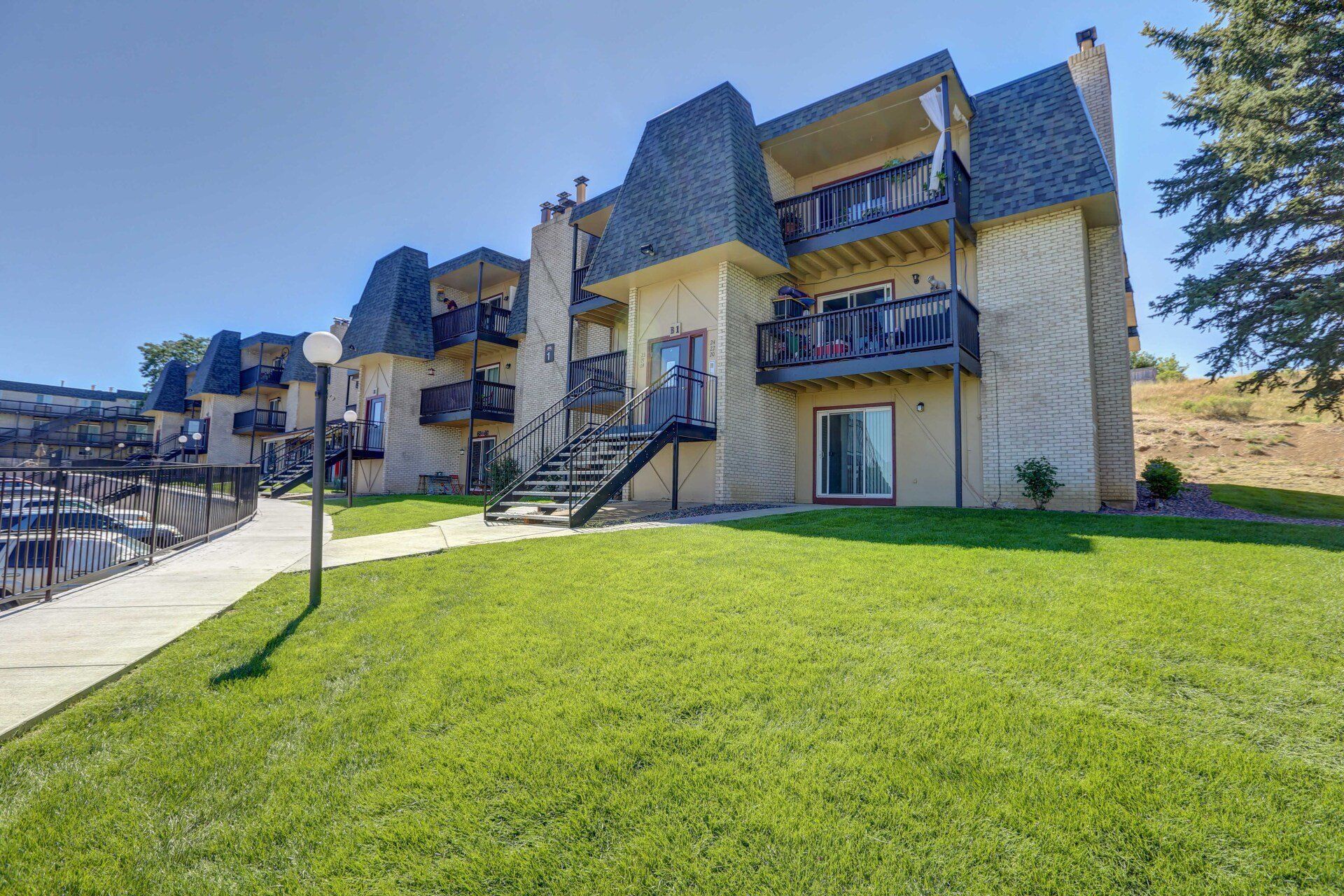 A large apartment building with a lush green lawn in front of it.