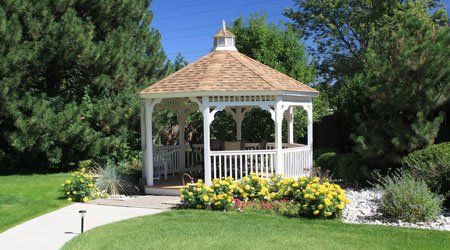 A white gazebo is sitting in the middle of a lush green field.