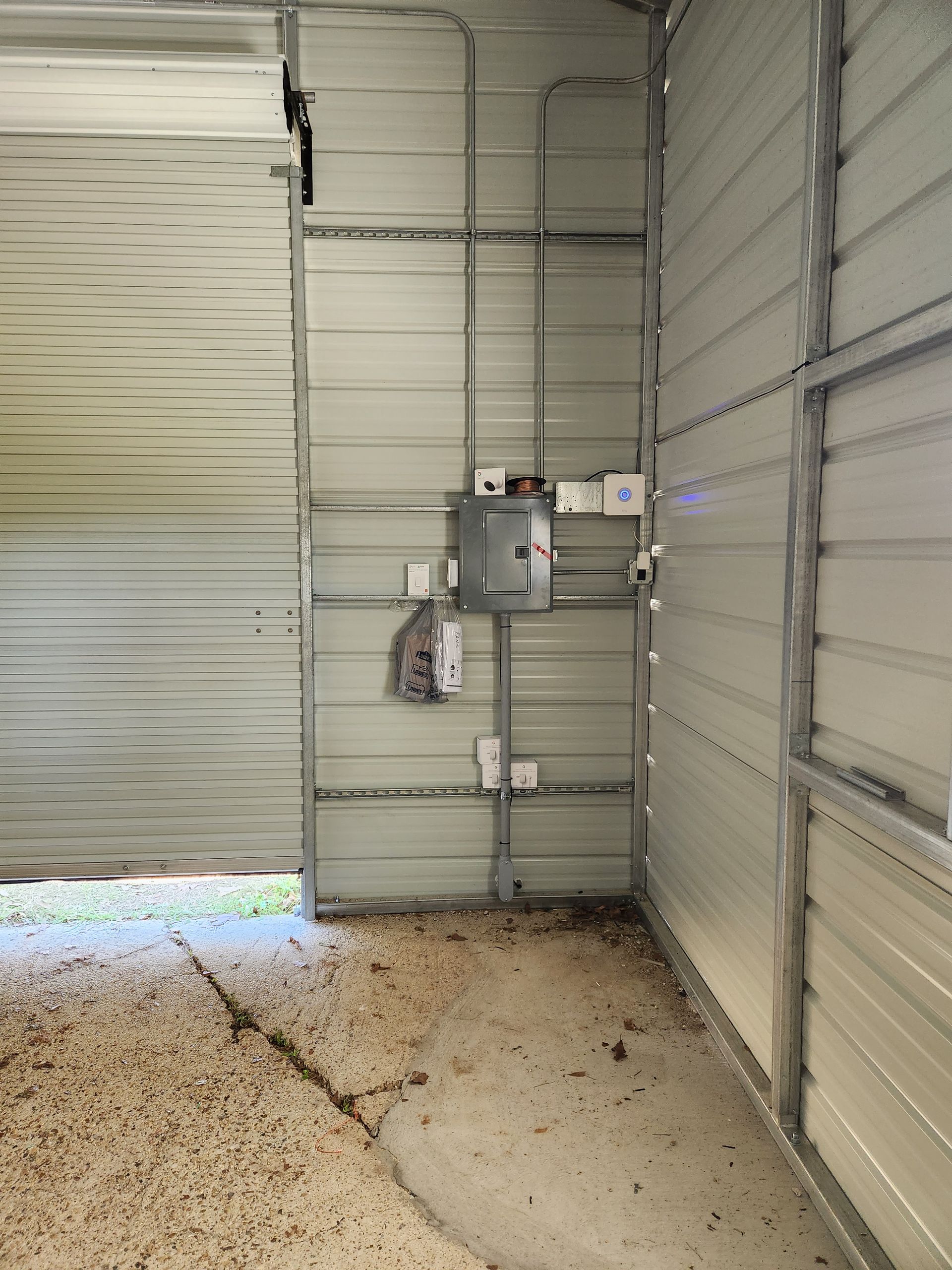 A garage with a door open and a box on the wall.