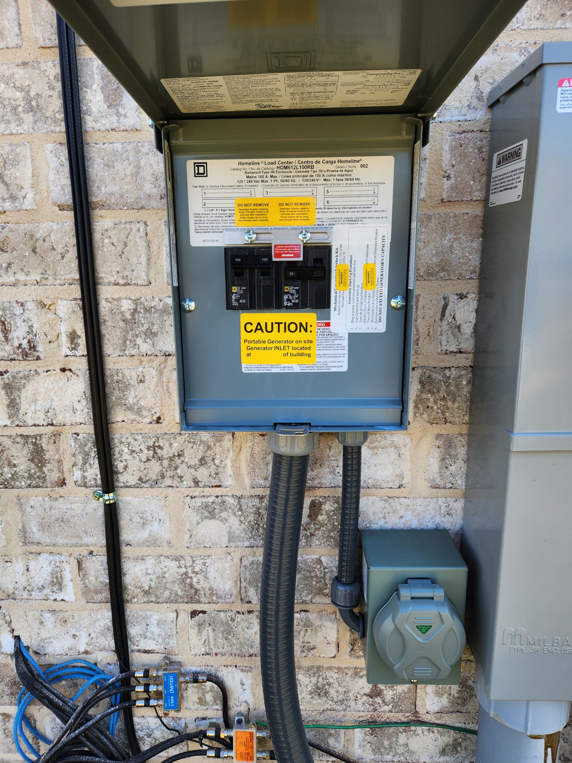 A electrical box is attached to a brick wall.