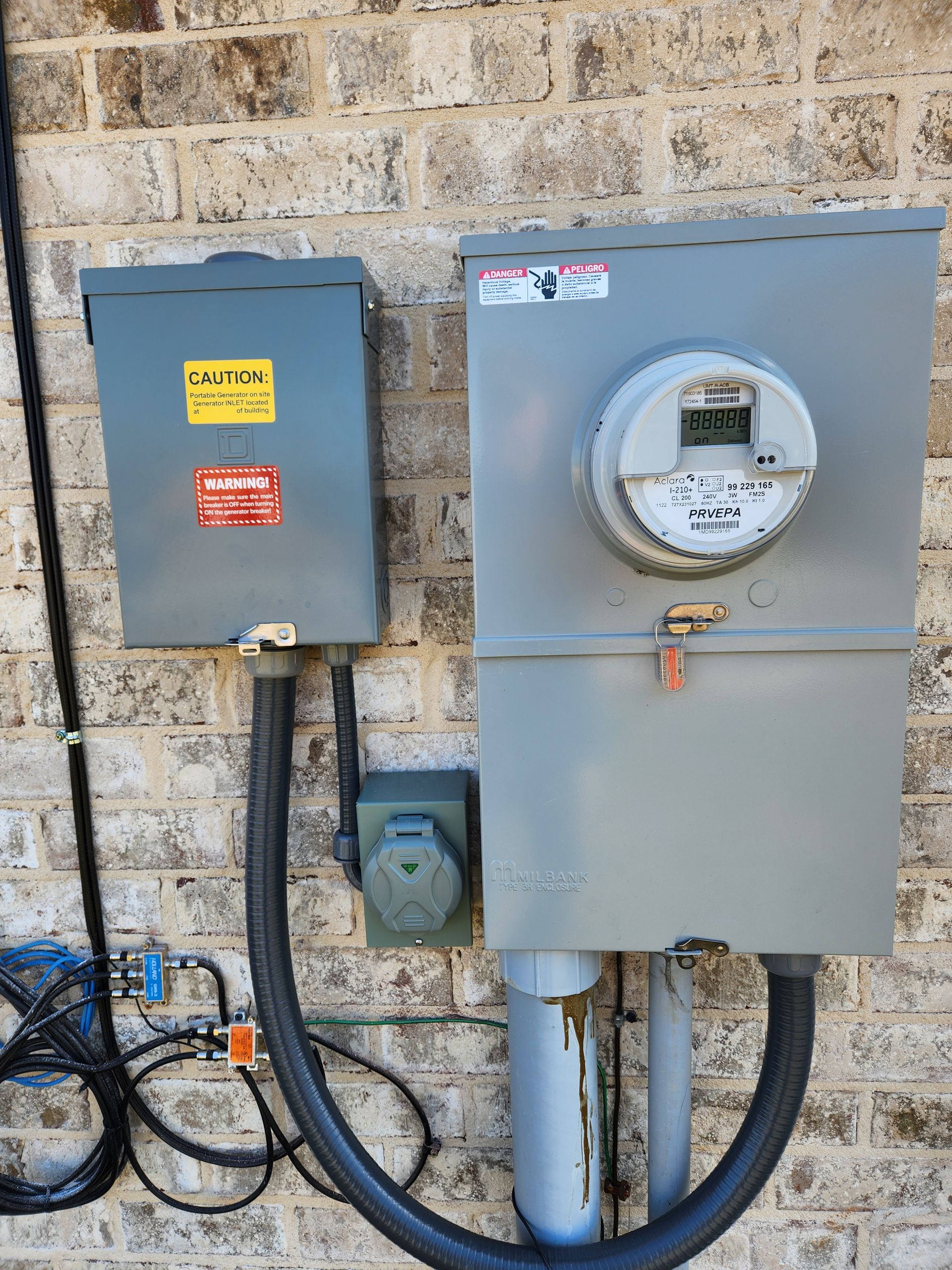 A brick wall with a meter and a box attached to it.